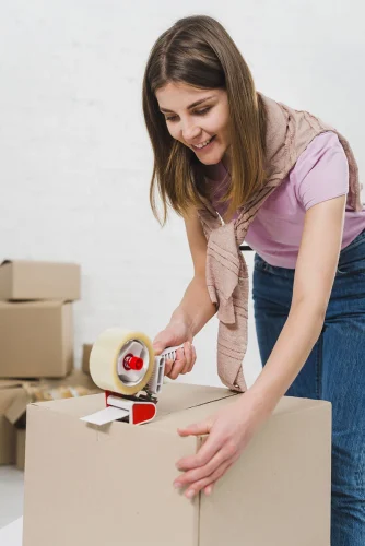 sorrindo-mulher-jovem-segurando-embalagem-maquina-e-selando-caixas-cartao-com-fita-adesiva